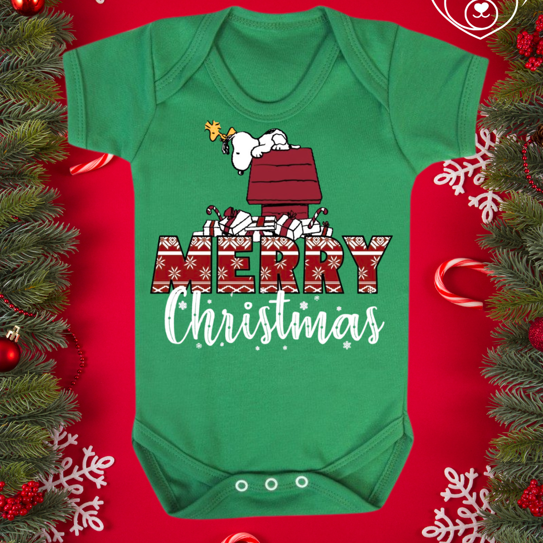 Green baby onesie with Christmas design on a red background with festive decorations
